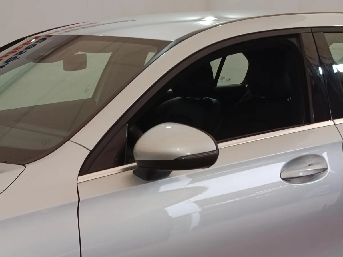 Vue latérale côté gauche d'une Mercedes Classe A 180 d Business Line gris clair avec rétroviseur et poignée de porte visibles.