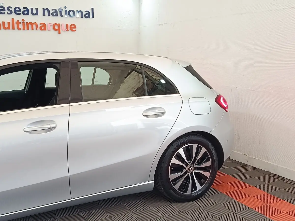 Vue côté droit arrière d'une Mercedes Classe A gris clair avec jantes alliage distinctives et feux arrière allumés.
