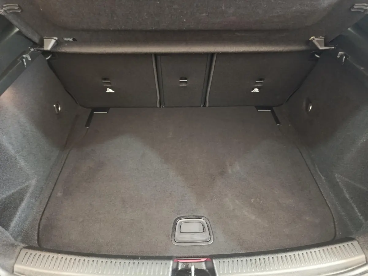 Vue plongeante sur le coffre spacieux et vide d'une Mercedes Classe A gris clair, avec banquette arrière rabattable.