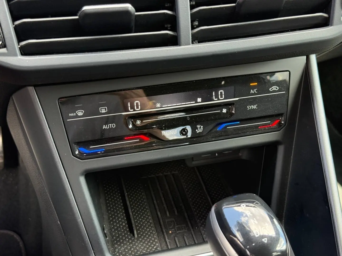 Gros plan sur la console centrale du Volkswagen Taigo gris, montrant la climatisation bi-zone et le levier de boîte automatique.