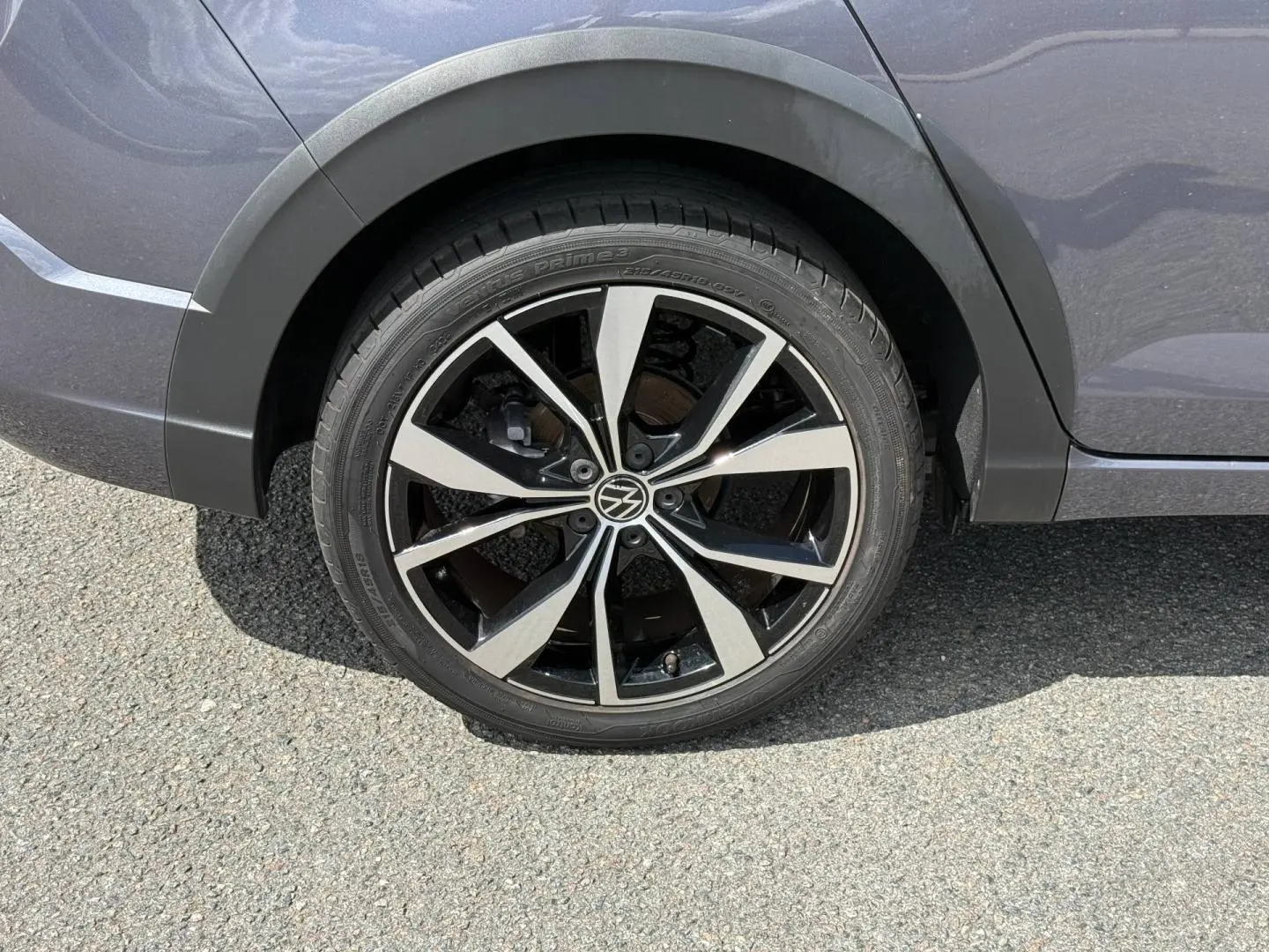 Gros plan sur la roue arrière droite du Volkswagen Taigo gris, avec jante alliage noire et argentée au design R-Line.