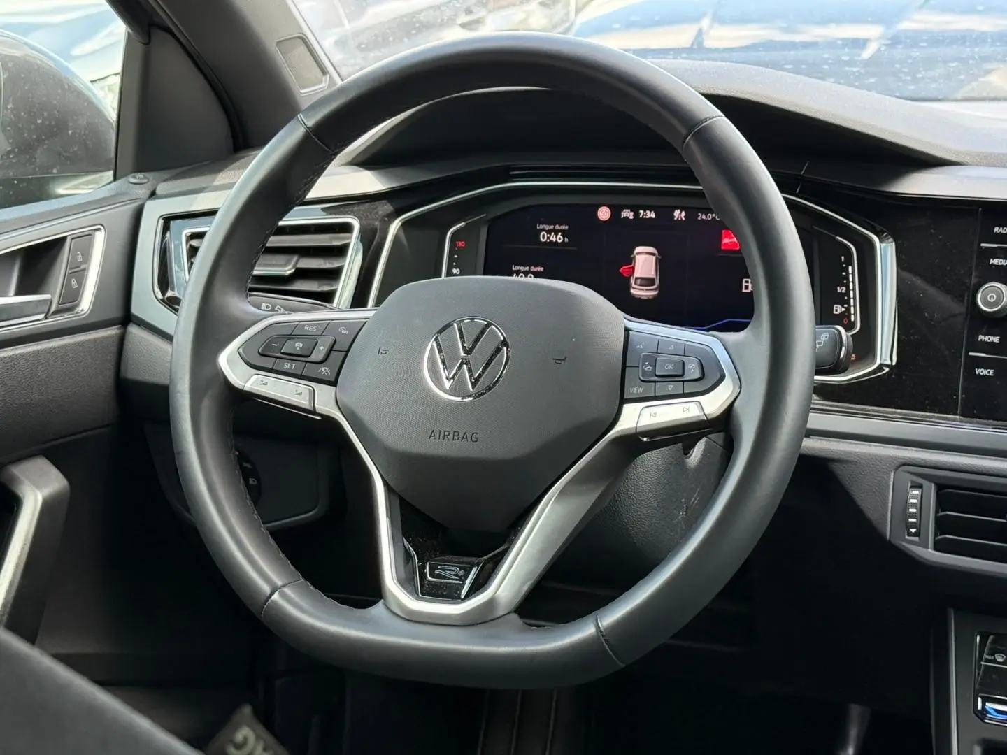 Vue rapprochée du volant cuir multifonction noir du Volkswagen Taigo 1.0 TSI 116ch R-Line avec tableau de bord numérique.