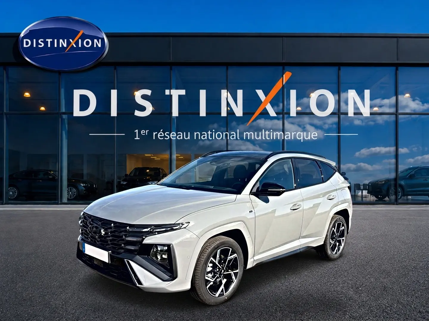 Hyundai Tucson 2026 blanc en 3/4 avant droit avec calandre noire et jantes alliage devant showroom Distinxion.