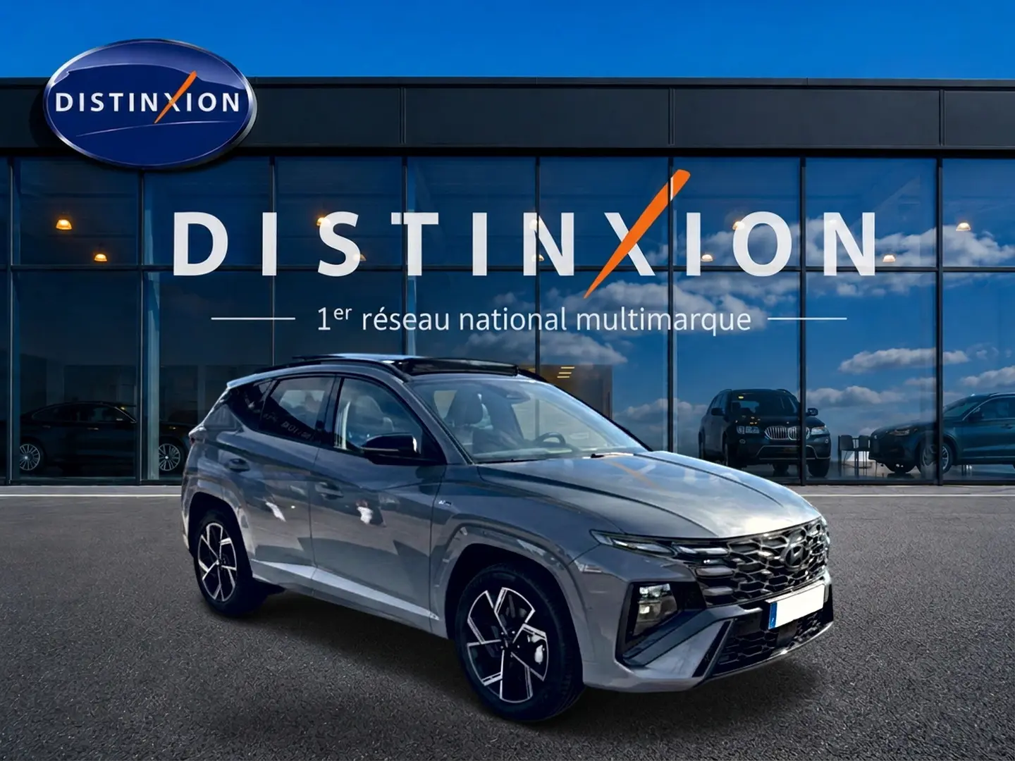 Hyundai Tucson 2026 gris shadow en 3/4 avant droit, avec calandre chromée et jantes alu distinctives.