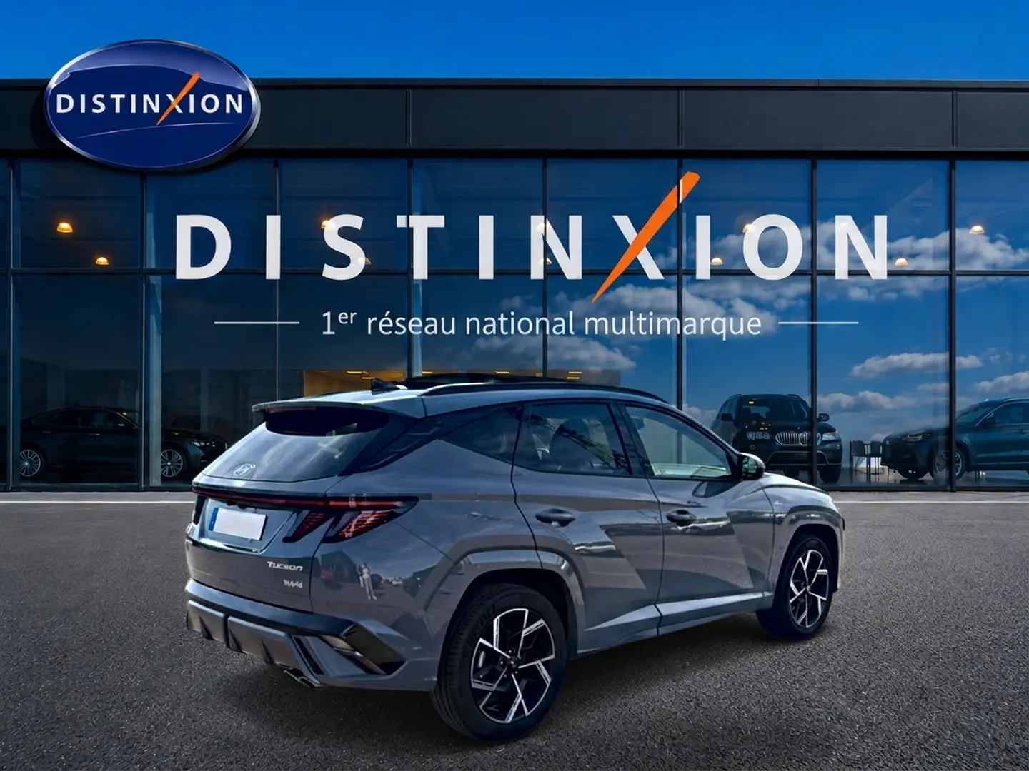 Vue 3/4 arrière droite du Hyundai Tucson gris shadow avec jantes alu noires et toit panoramique visible.