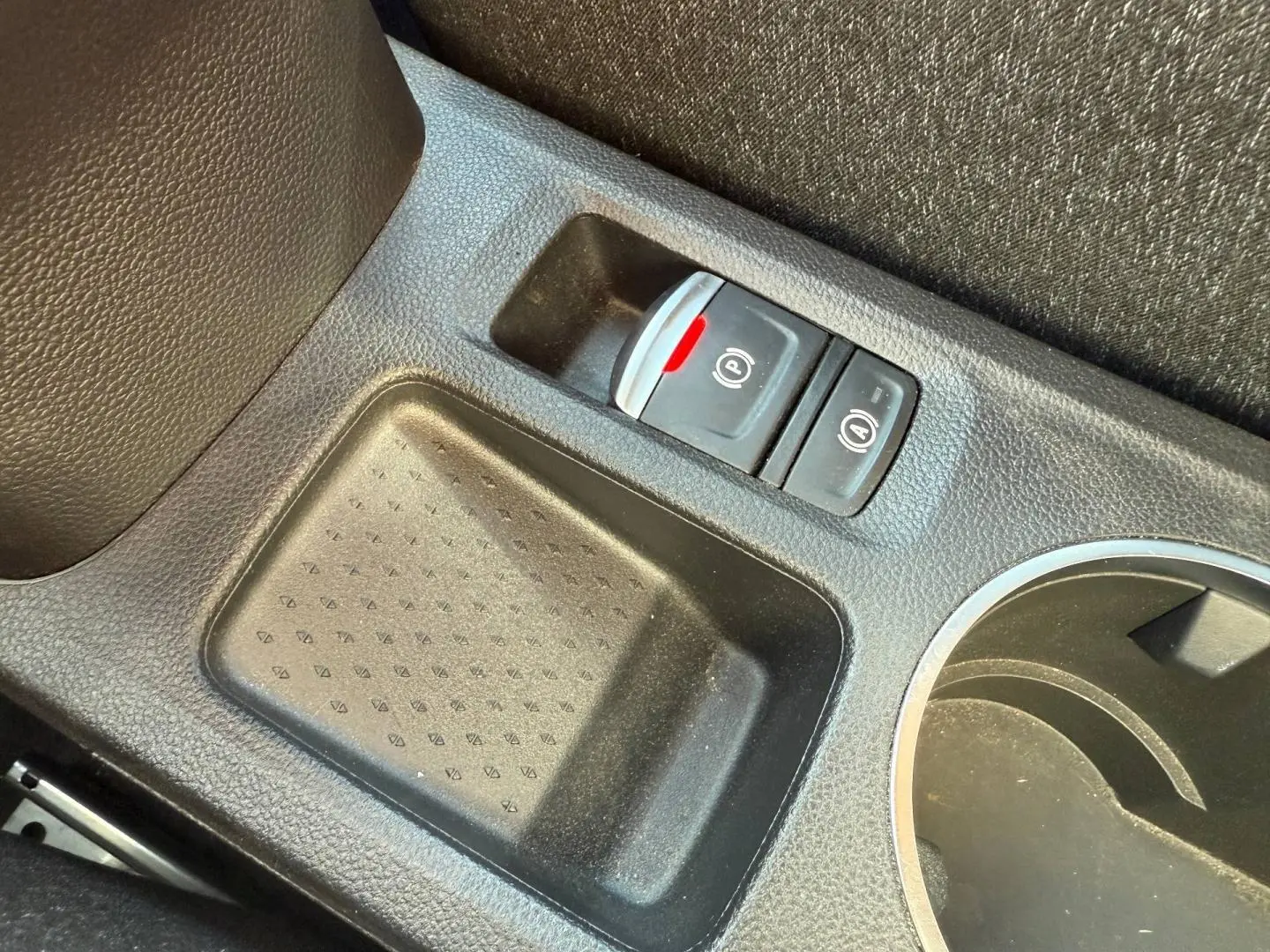 Gros plan sur la console centrale noire du Renault Captur 2025, avec bouton frein à main électrique et porte-gobelets.