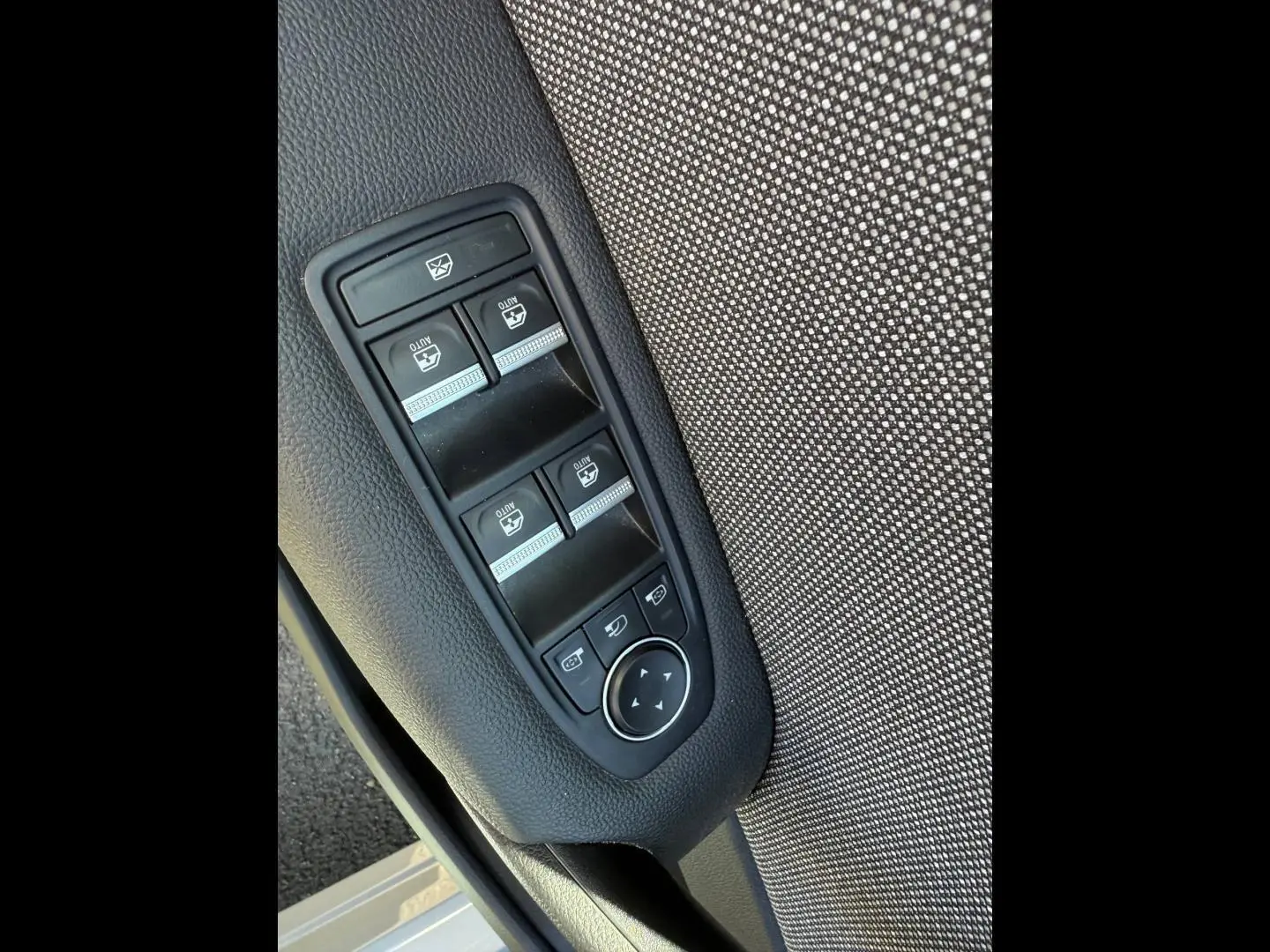 Panneau de commandes des vitres électriques et rétroviseurs sur la porte avant gauche d'un Renault Captur gris.
