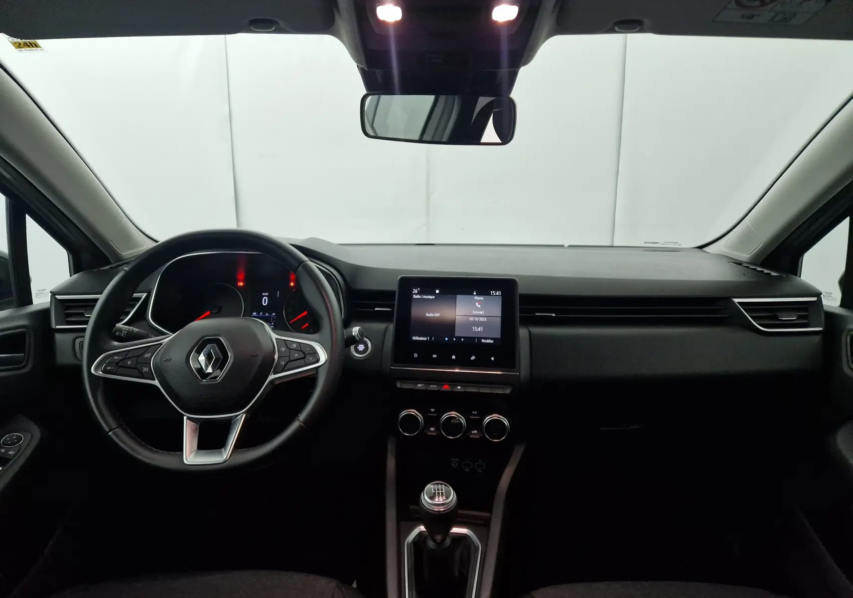 Vue intérieure avant de la Renault Clio V 1.0 TCE 90 Zen 2021, tableau de bord noir avec écran tactile et levier de vitesse manuel.