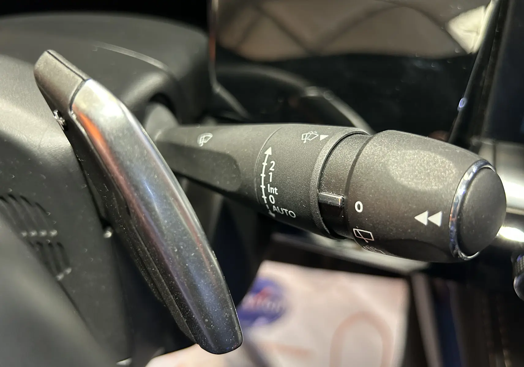 Gros plan sur la commande des essuie-glaces à gauche du volant dans l’habitacle d’une Peugeot 508 SW 2024.