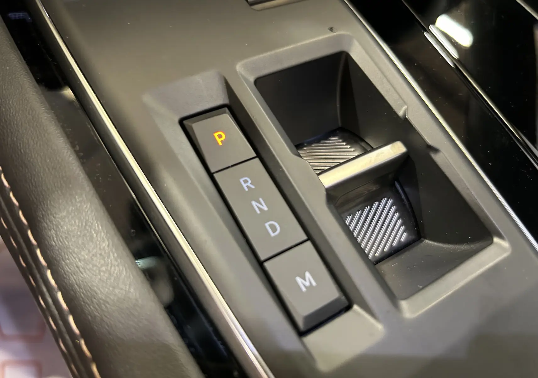 Gros plan sur la commande de boîte automatique noire avec boutons P, R, N, D, M dans un Peugeot 508 SW 2024 gris artense.