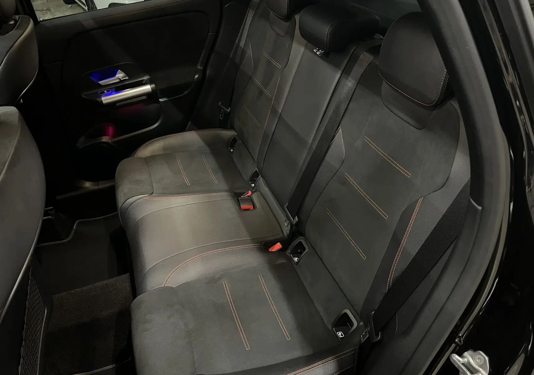 Vue intérieure arrière droite des sièges noirs avec surpiqûres rouges du Mercedes GLA 250E AMG Line 2023 en Noir Cosmos.
