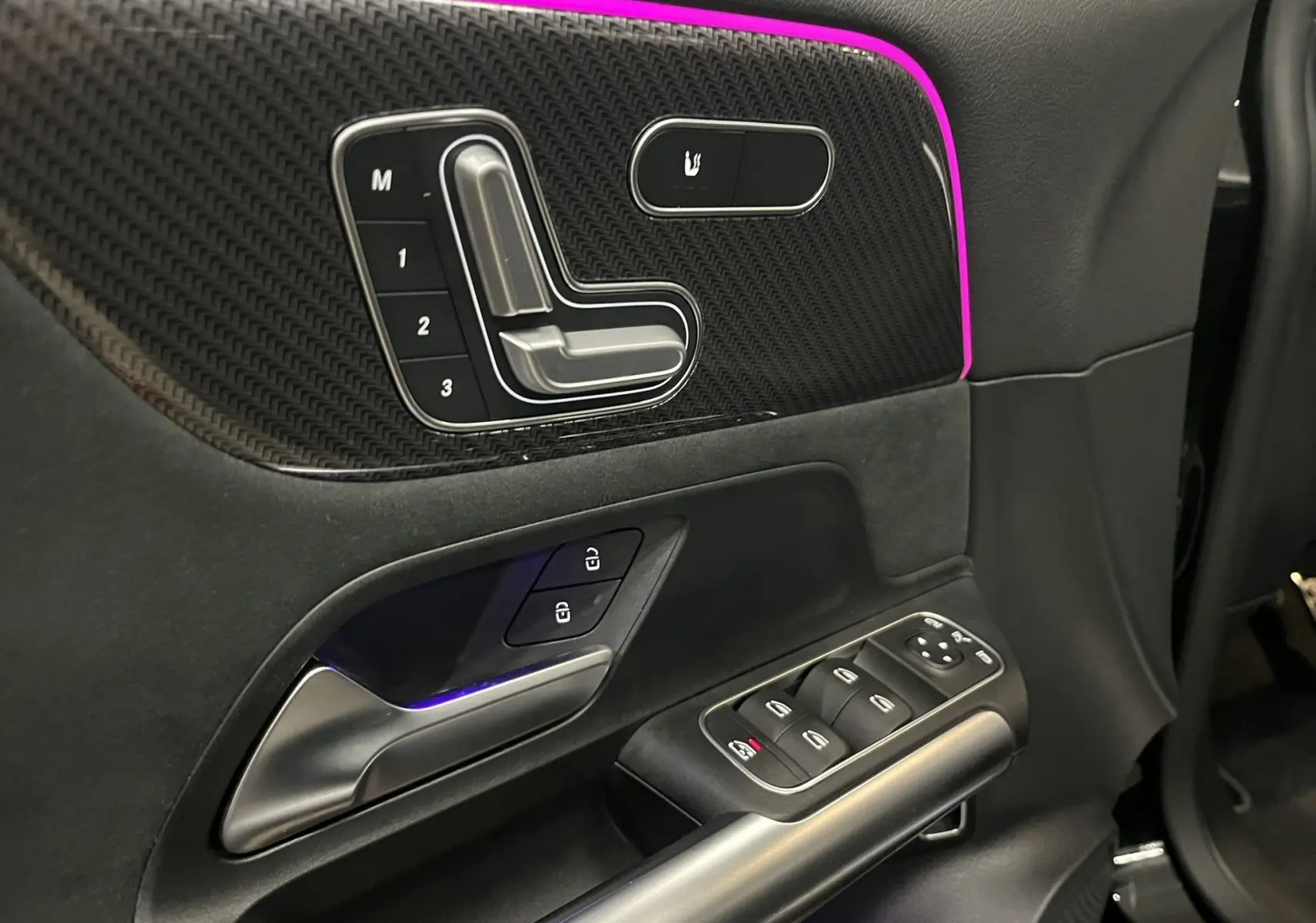 Détail de la porte côté gauche du Mercedes GLA 250E AMG Line 2023, avec commandes sièges, surpiqûres rouges et éclairage d'ambiance violet.