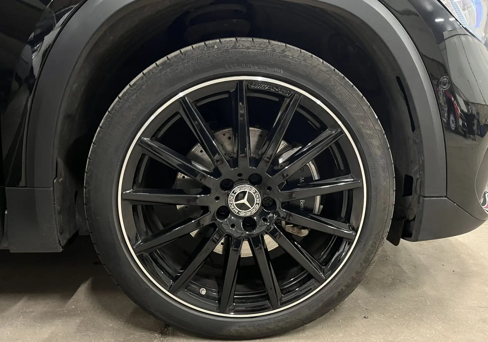 Gros plan sur la roue avant gauche noire brillante du Mercedes GLA 250E AMG Line avec jante à rayons fins et logo Mercedes central.