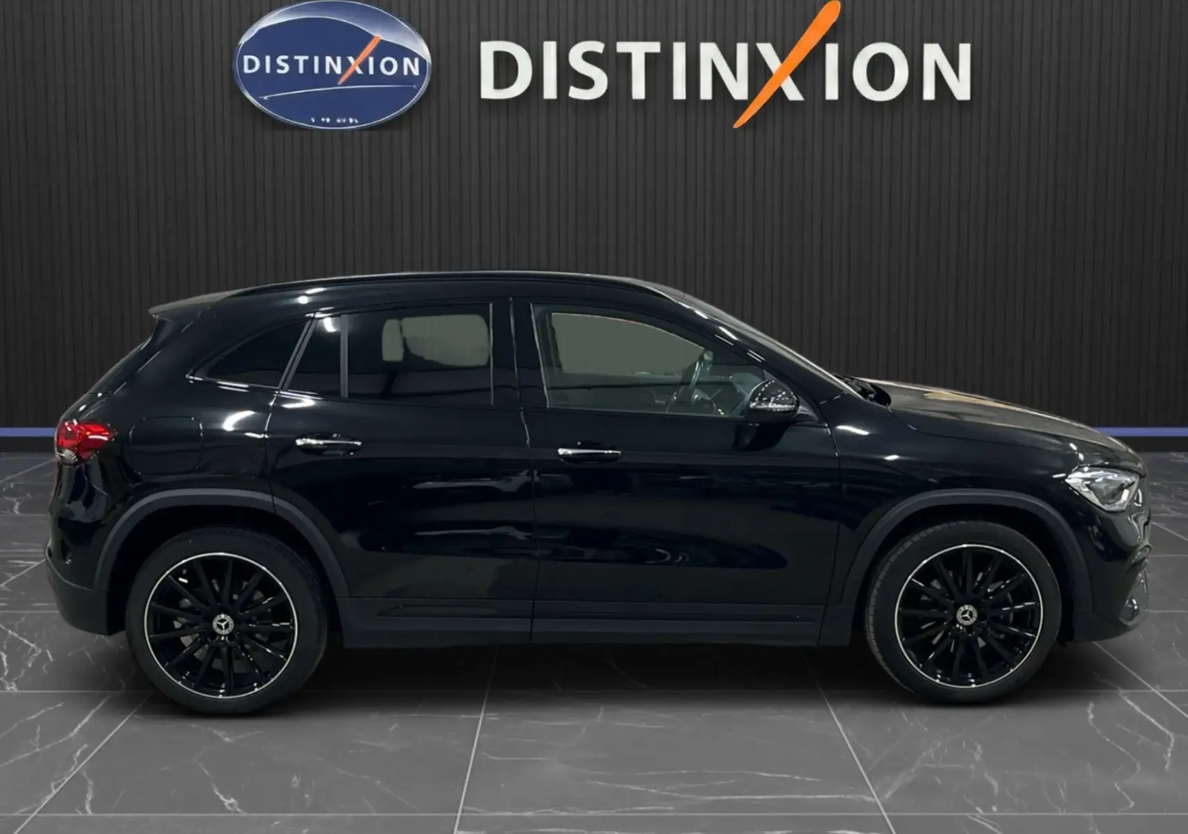 Vue de profil côté gauche d'un Mercedes GLA 250E AMG Line noir Cosmos avec jantes noires et vitres teintées.