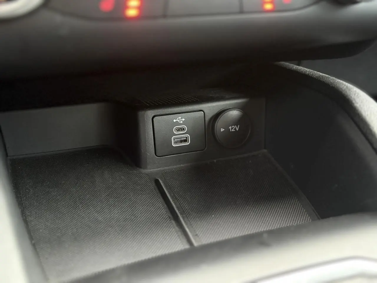 Détail de la console centrale du Ford Kuga 2024 noir Obsidien, avec ports USB et prise 12V visibles.