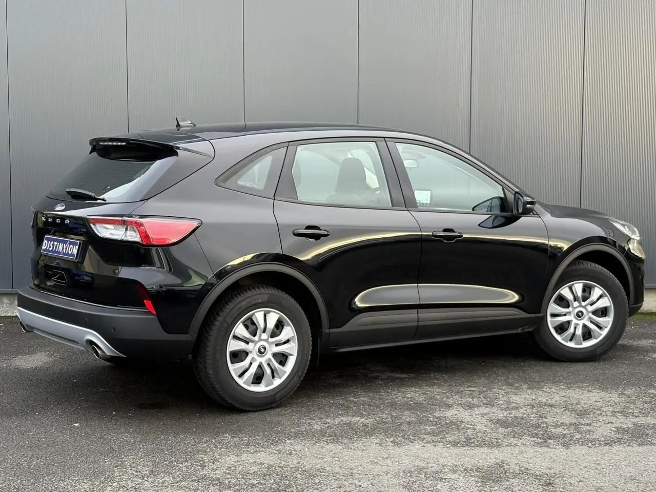 Vue 3/4 arrière droite d'un Ford Kuga 2024 noir obsidien avec jantes argentées et feux arrière allongés.