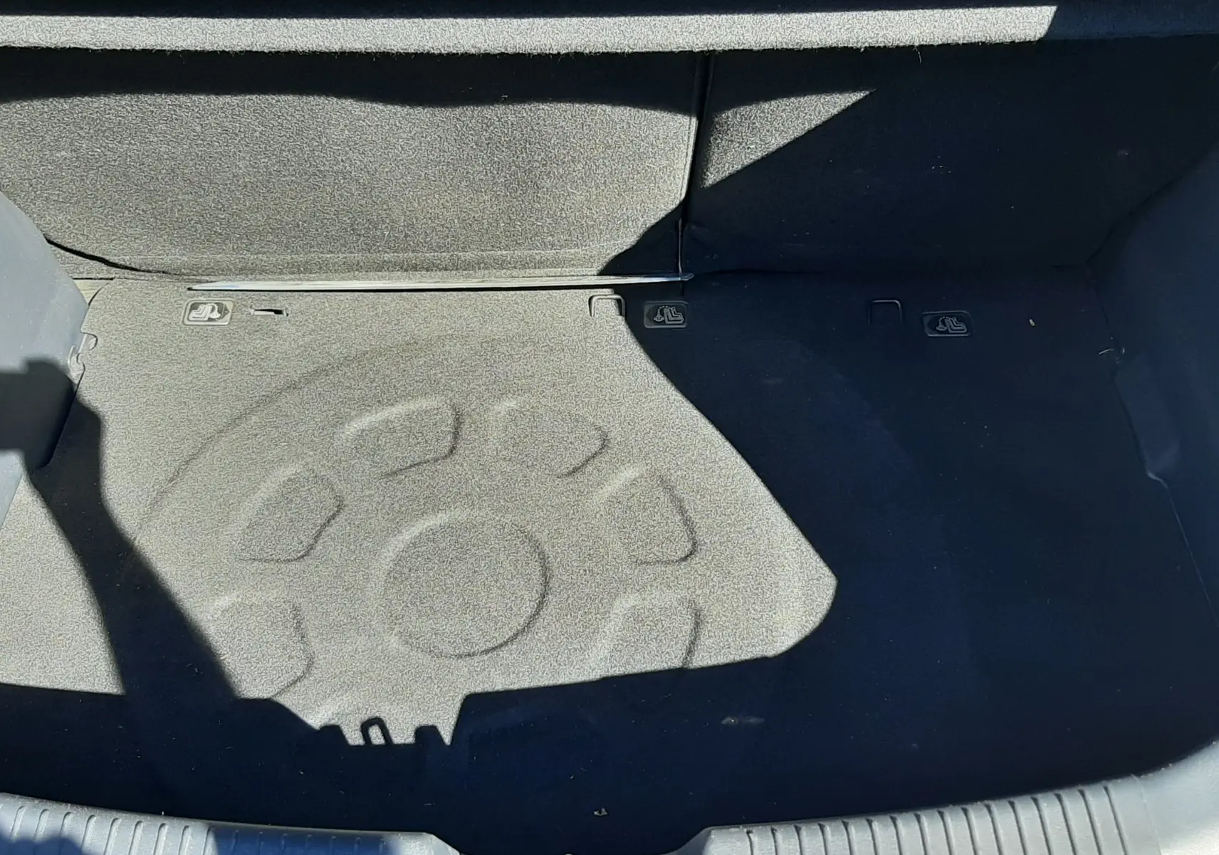 Vue plongeante sur le coffre gris de la Kia Rio 2016, montrant le revêtement et les fixations pour siège enfant.