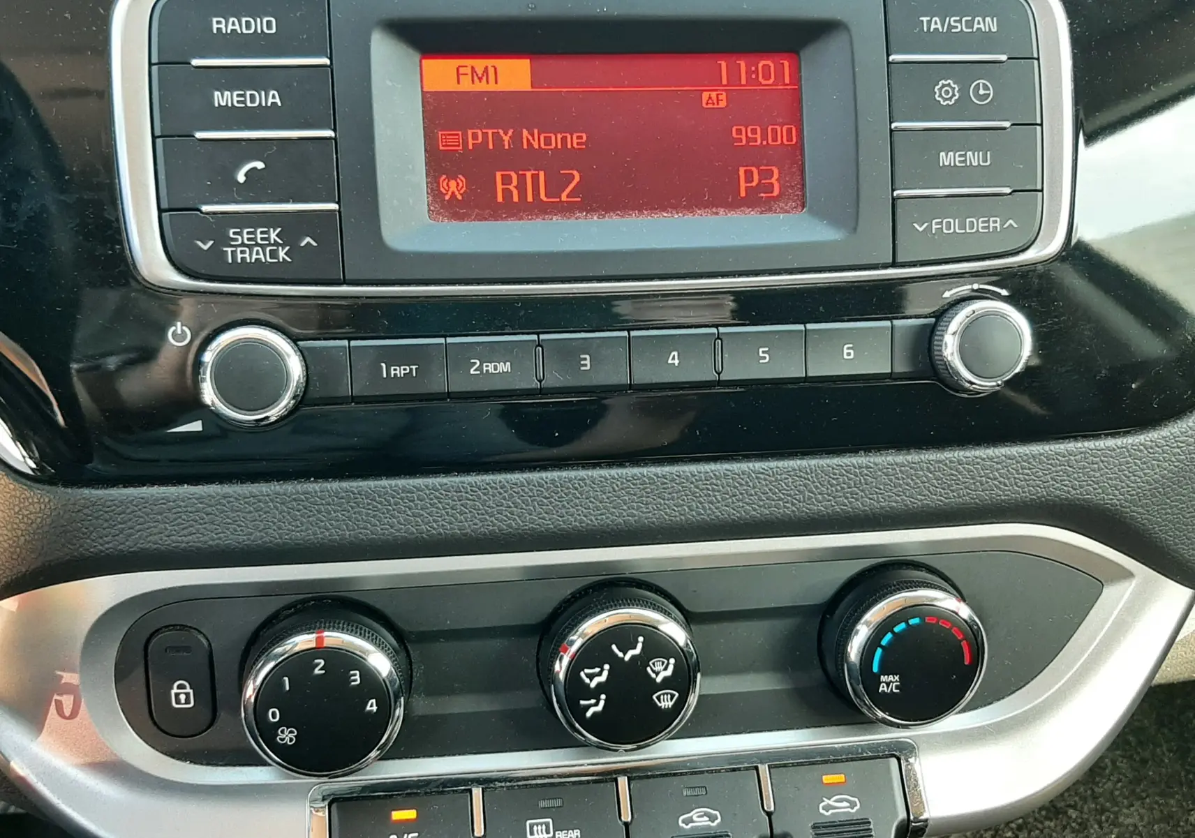 Vue rapprochée du tableau de bord de la Kia Rio grise 2016, montrant la radio et les commandes de climatisation.