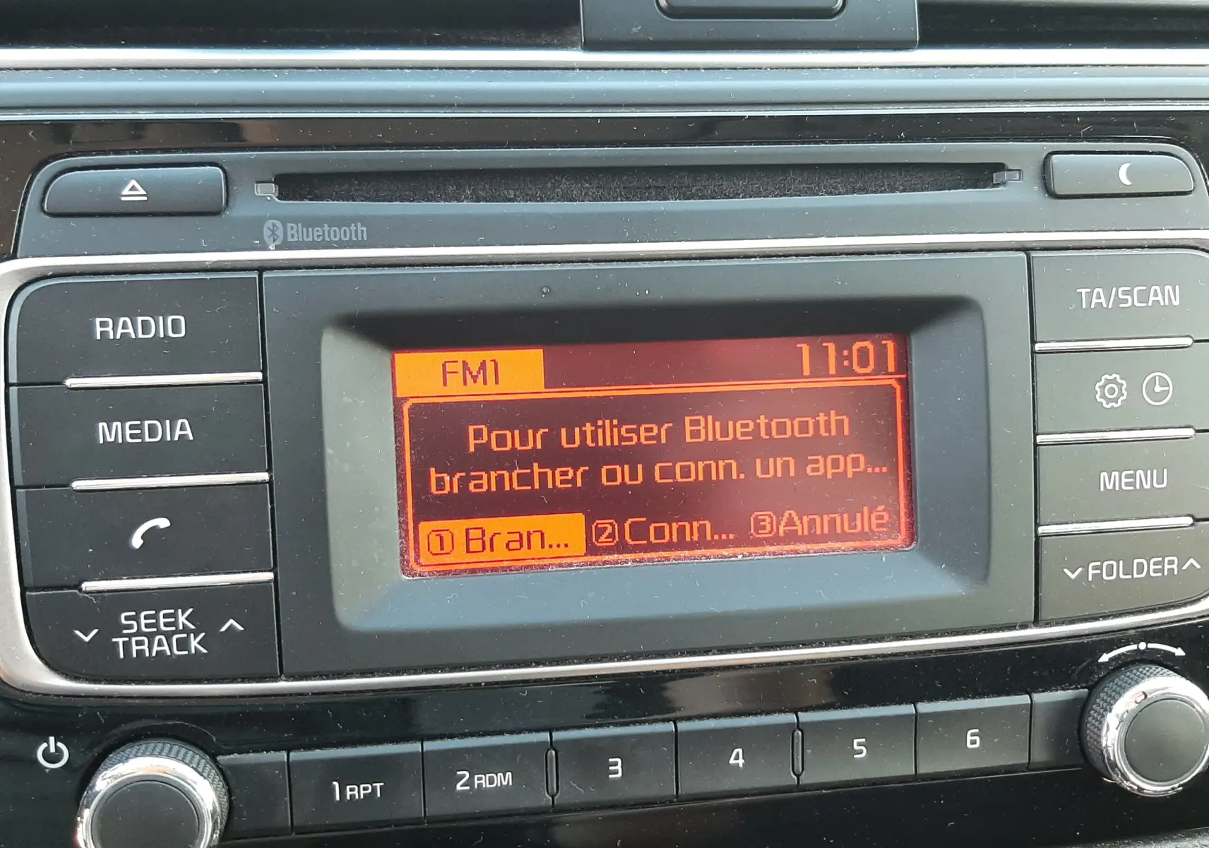 Gros plan sur l’écran central du tableau de bord de la Kia Rio grise 2016, affichant le menu Bluetooth en orange.