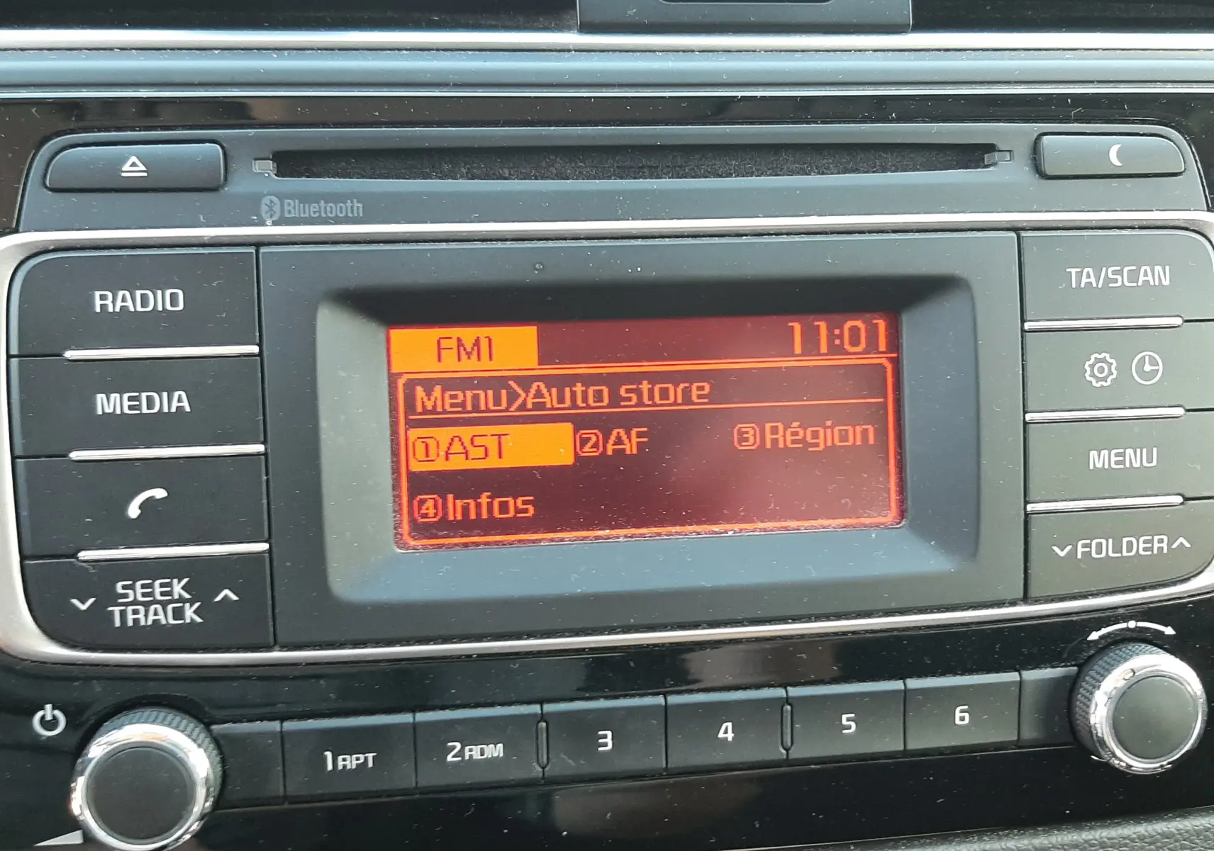 Vue rapprochée de la console centrale de la Kia Rio grise 2016, affichant l'écran radio FM avec menu Auto store.