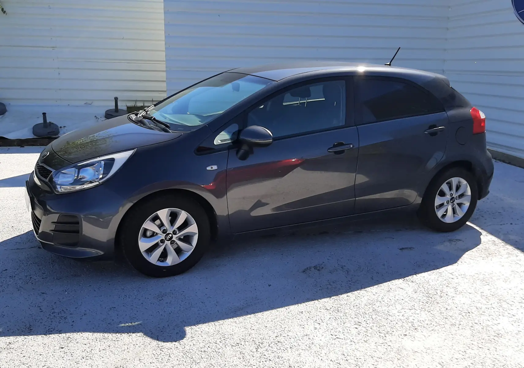 KIA Rio 1.2 85CH ACTIVE 2016 vue de profil côté gauche, compacte grise avec vitres teintées et jantes alliage.