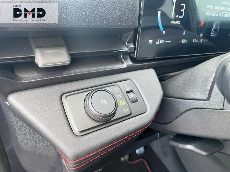 Gros plan sur la commande des phares avec molette et éclairage d'ambiance rouge dans l'habitacle du Ford Puma noir Agate.