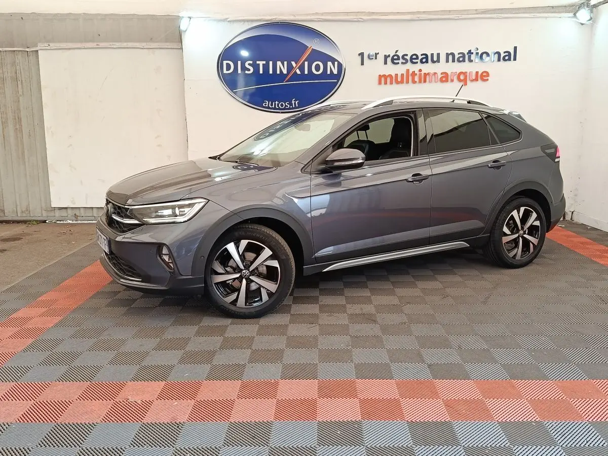 Vue de profil côté gauche du Volkswagen Taigo gris foncé 2023 avec jantes alliage et vitres teintées en showroom.