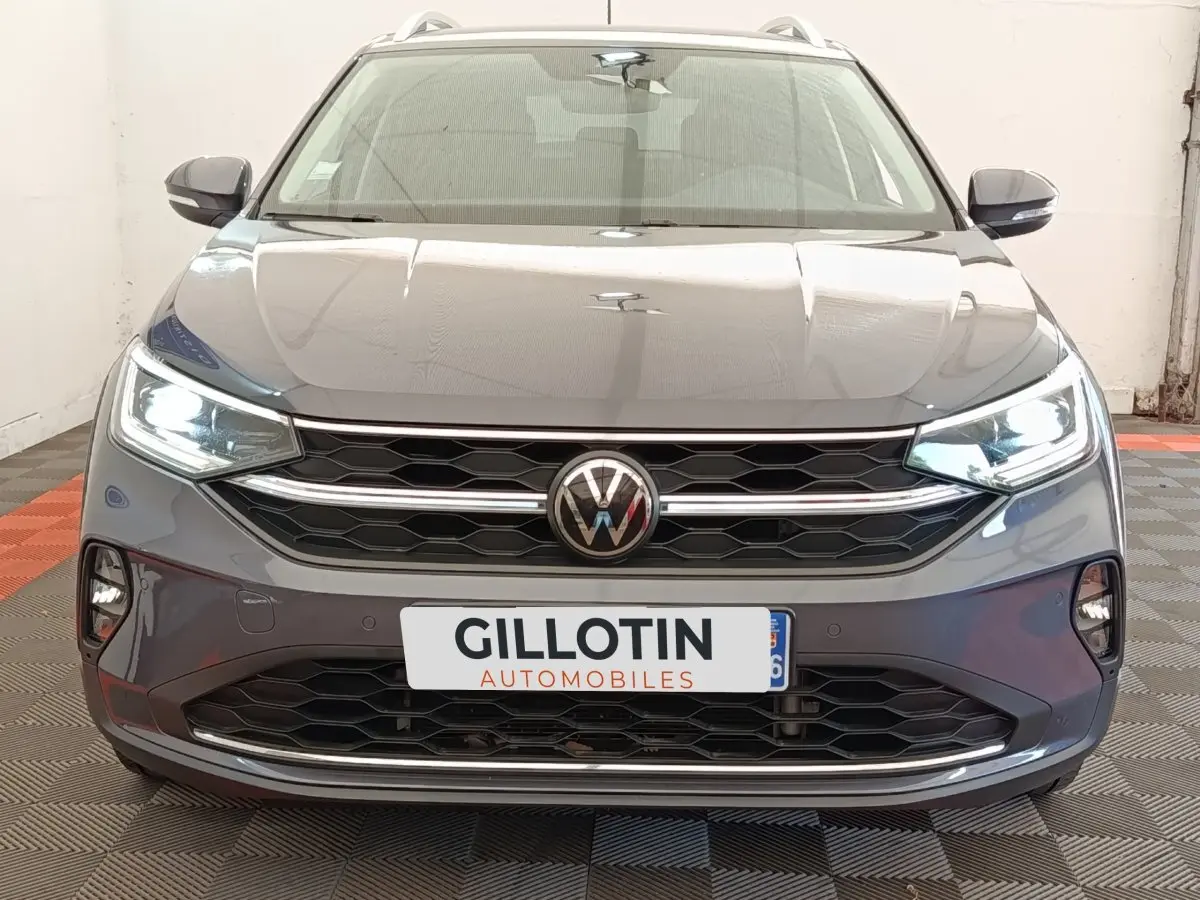 Vue frontale d’un Volkswagen Taigo gris foncé 2023 avec phares LED allumés et calandre hexagonale distinctive.