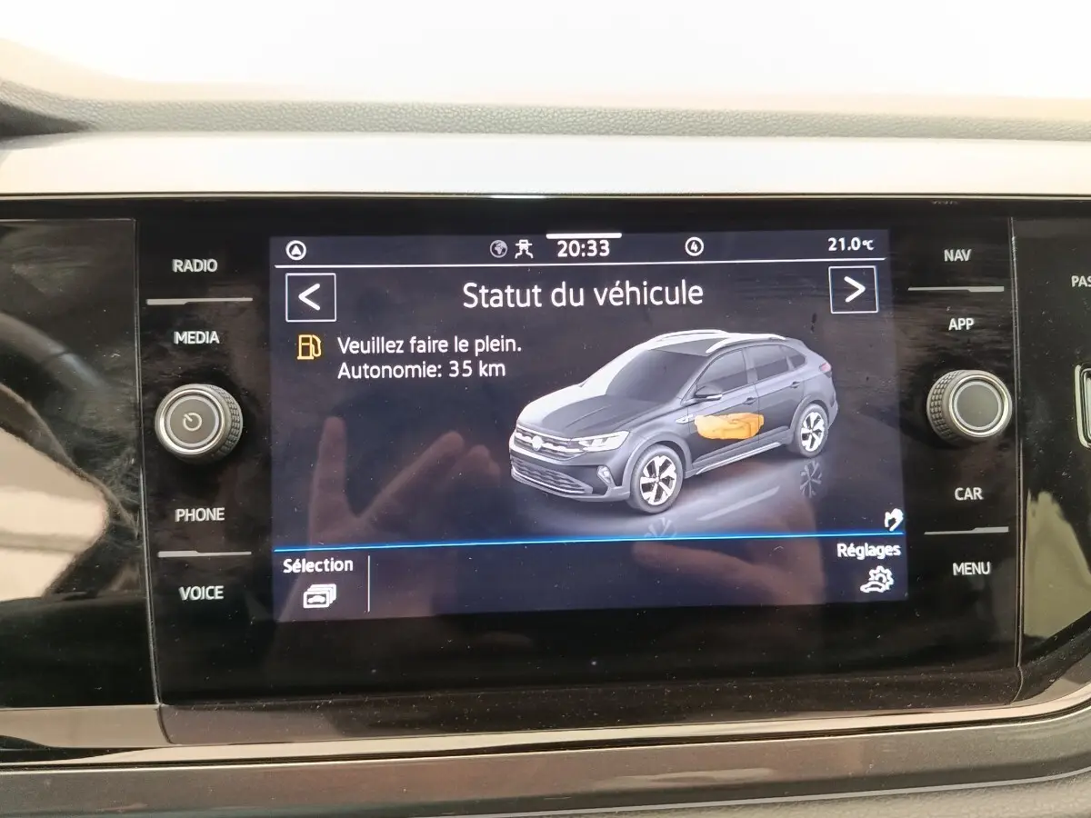 Écran tactile central affichant le statut du véhicule Volkswagen Taigo gris foncé en vue 3/4 avant droite.