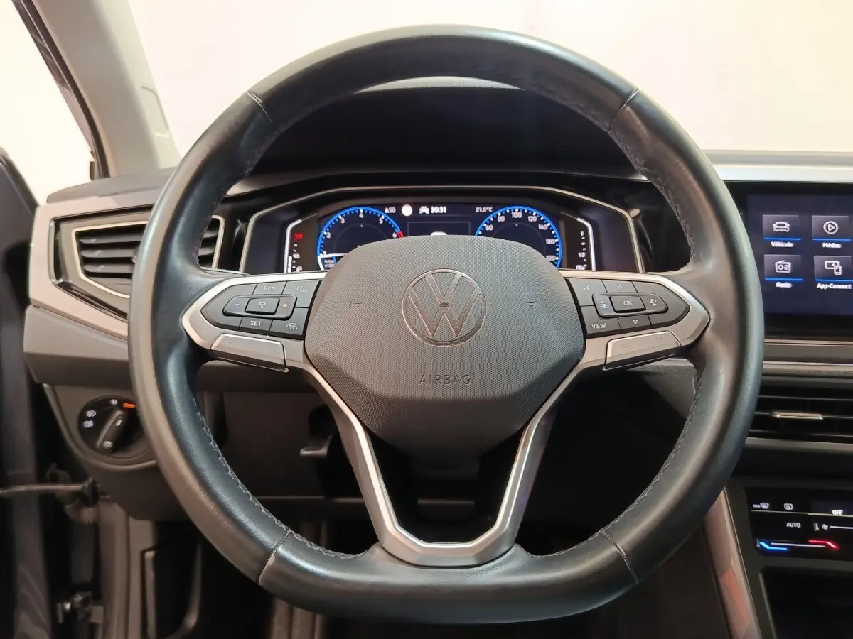 Vue rapprochée du volant en cuir noir du Volkswagen Taigo 1.5 TSI 150 DSG Style avec tableau de bord numérique allumé.