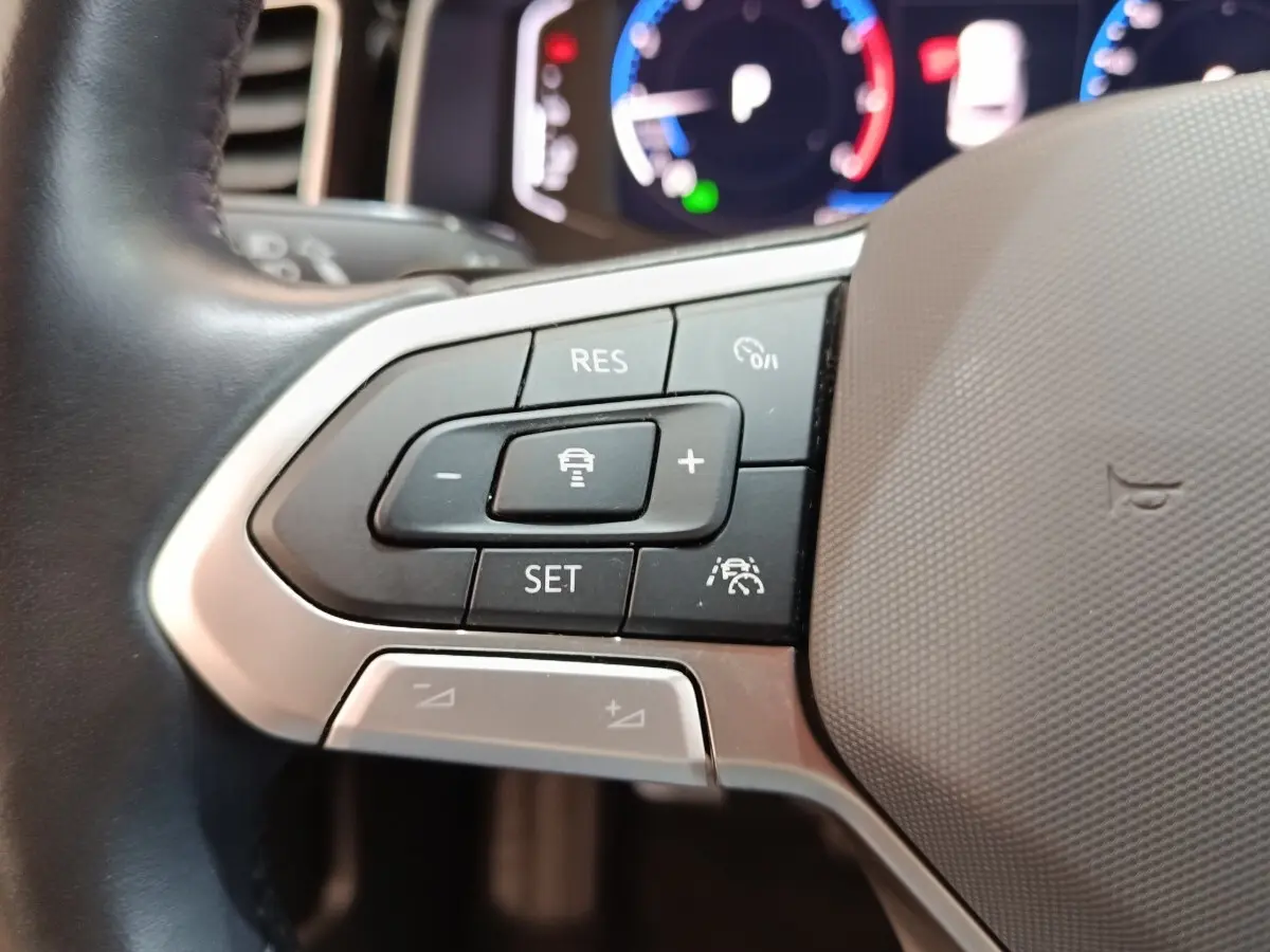 Gros plan sur les commandes de régulateur de vitesse au volant cuir alu du Volkswagen Taigo gris foncé 2023.