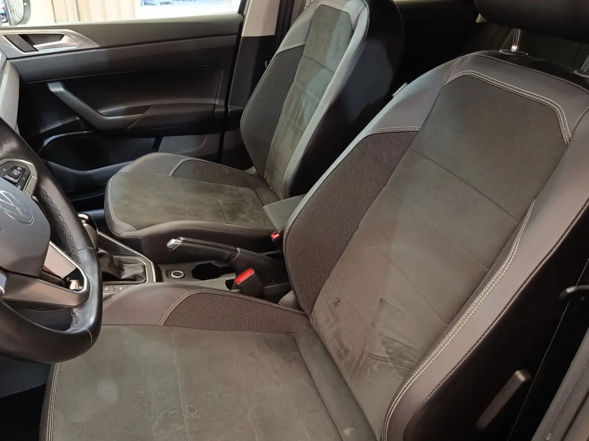 Vue intérieure côté conducteur du Volkswagen Taigo 2023, sièges tissu gris foncé avec surpiqûres claires.