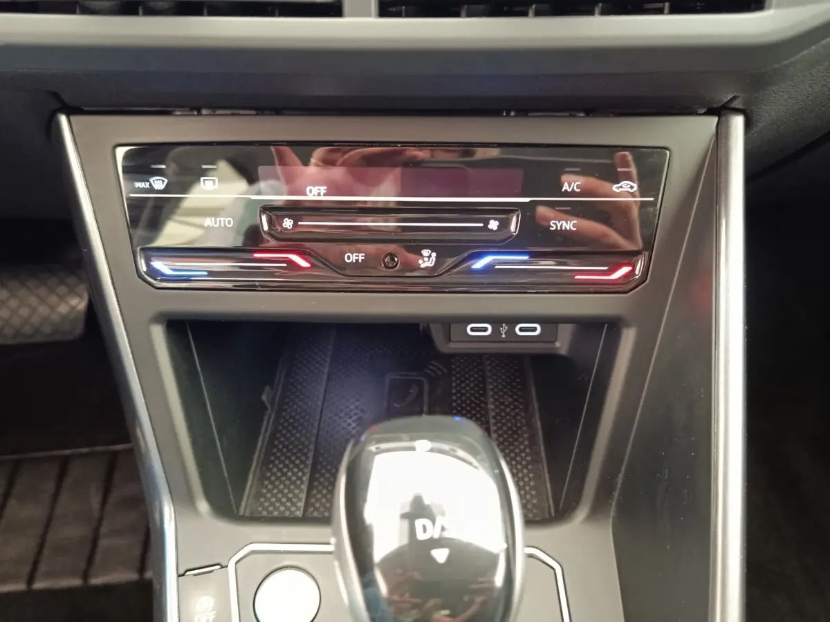 Vue rapprochée de la console centrale du Volkswagen Taigo 2023, avec commandes climatisation et levier de boîte auto brillant.