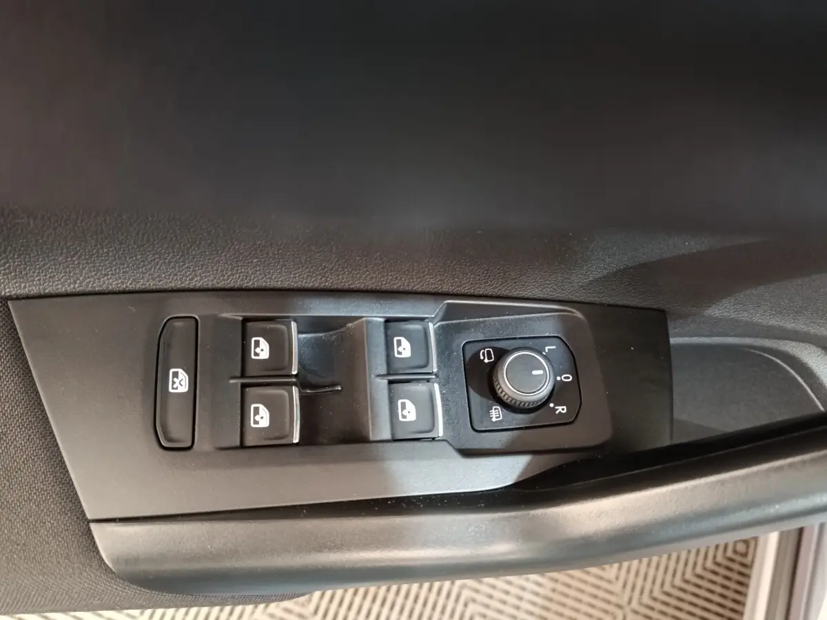 Gros plan sur les commandes de lève-vitres et réglage des rétroviseurs côté conducteur du Volkswagen Taigo gris foncé 2023.