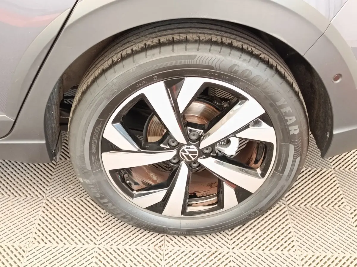Gros plan sur la roue avant droite gris foncé du Volkswagen Taigo 2023 avec jante alliage bicolore et logo VW central.
