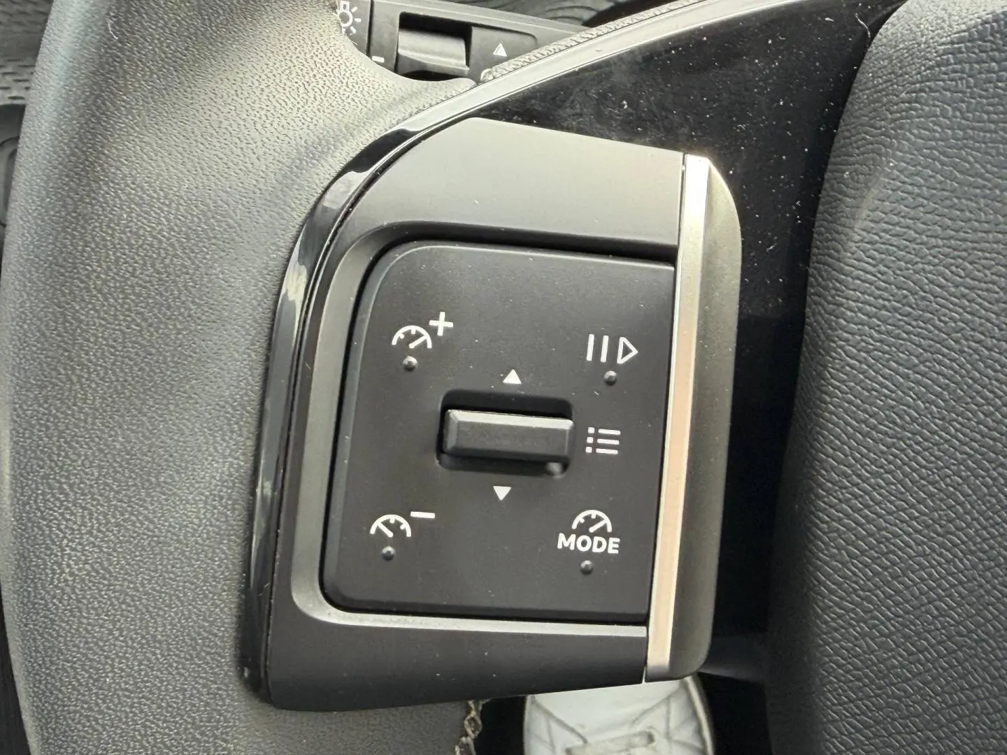 Gros plan sur les commandes de régulateur de vitesse à gauche du volant d’une Citroën C3 noire 2025.