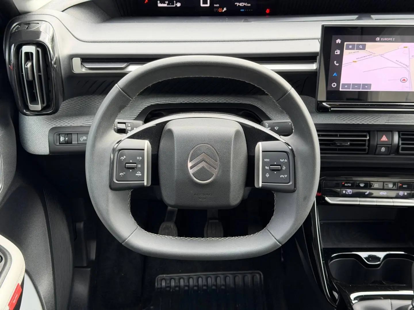Vue frontale du volant noir de la Citroën C3 1.2 Turbo 2025 avec commandes intégrées et écran tactile de navigation.
