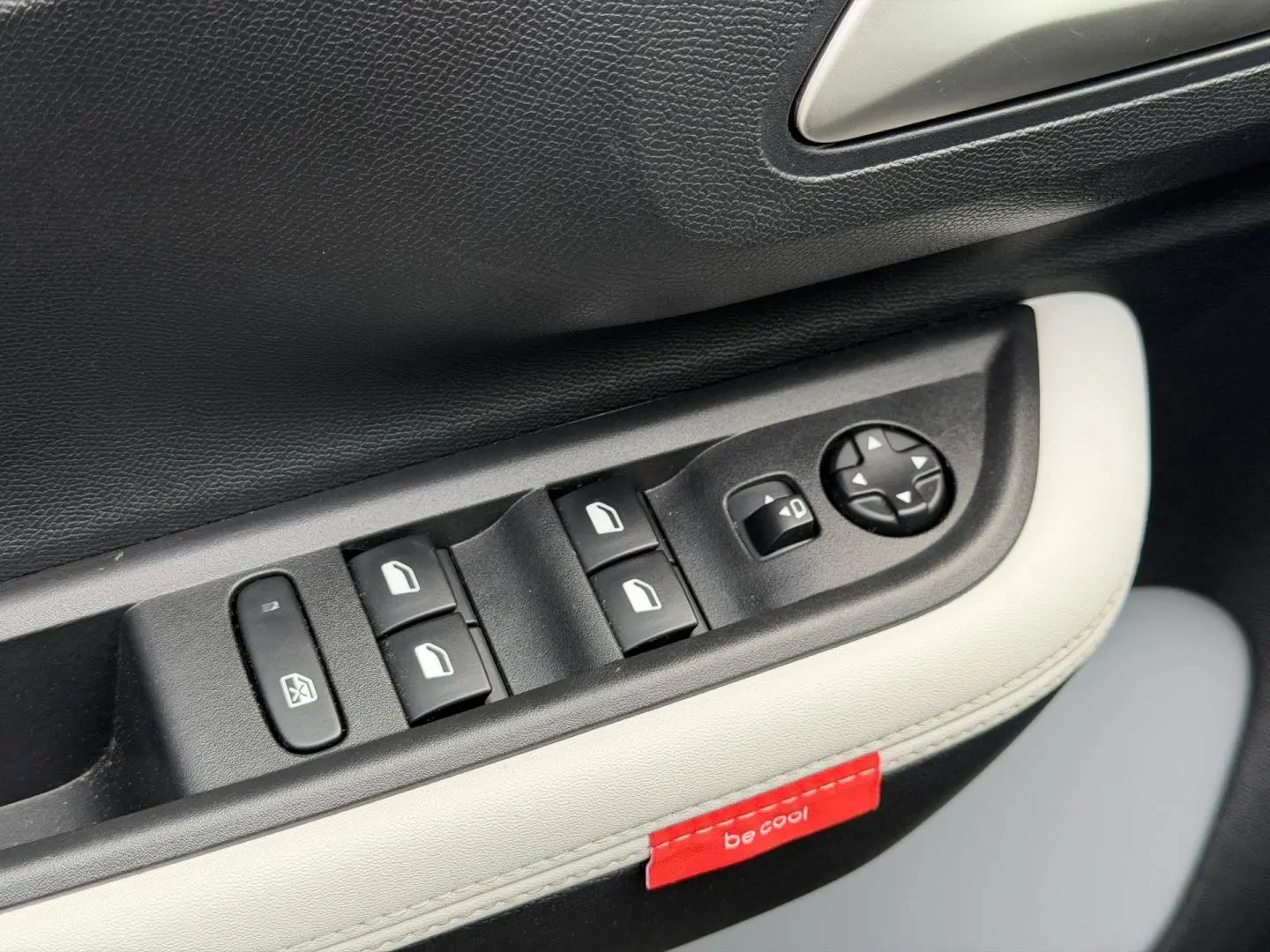 Détail des commandes de lève-vitres et réglage des rétroviseurs sur la portière intérieure noire et blanche du Citroën C3 2025.