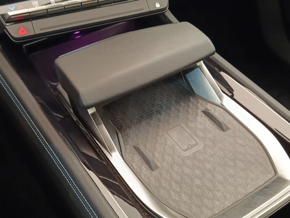 Détail de la console centrale noire du Renault Austral 2024 avec accoudoir et surface de recharge sans fil visible.