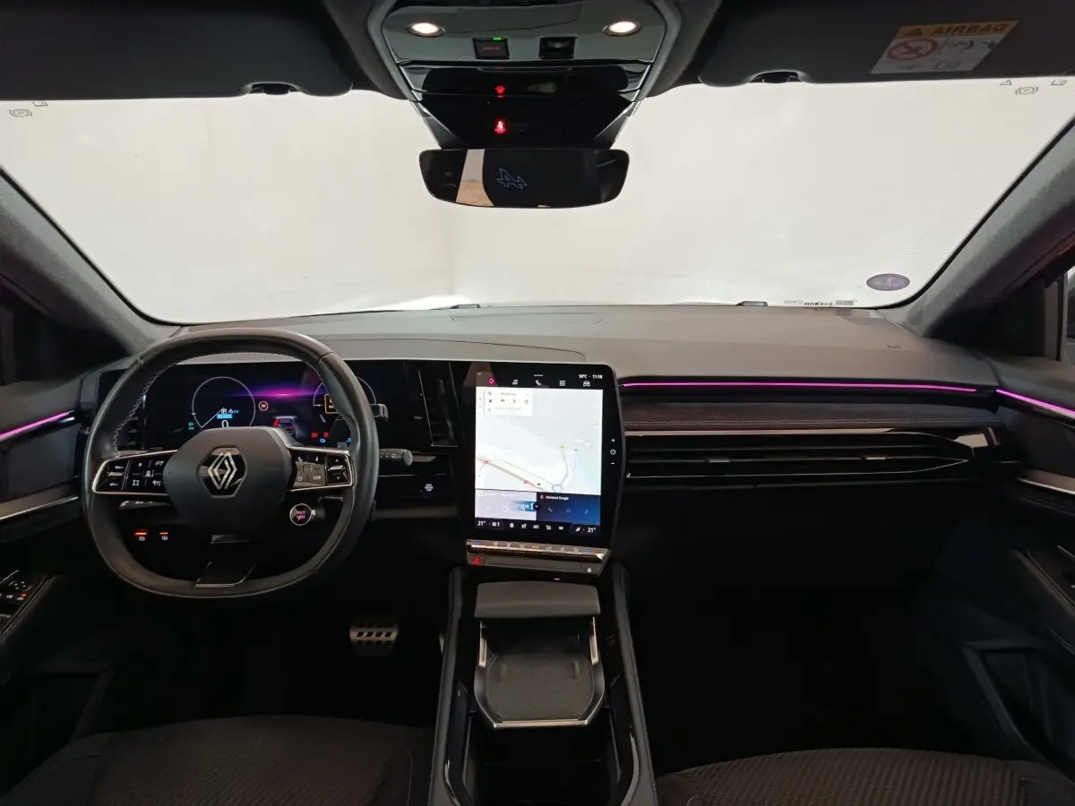 Vue intérieure avant du Renault Austral gris clair 2024, tableau de bord avec écran tactile vertical et éclairage d'ambiance violet.