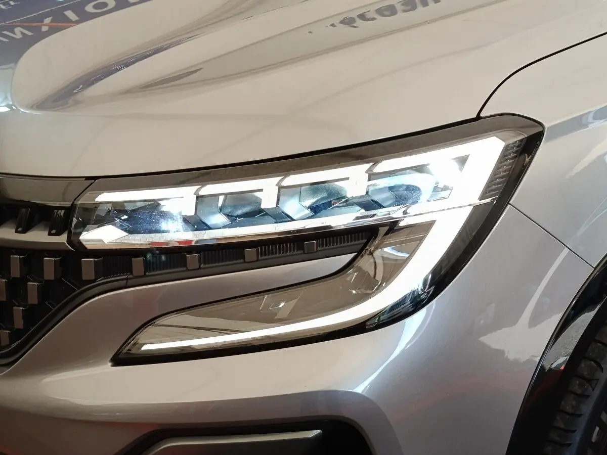 Gros plan sur le phare avant droit allumé du Renault Austral gris clair, soulignant le design LED distinctif.