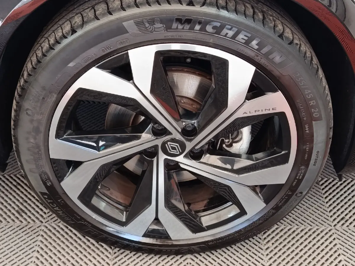 Gros plan sur la jante alu bicolore avec logo Alpine et pneu Michelin du Renault Austral gris clair.