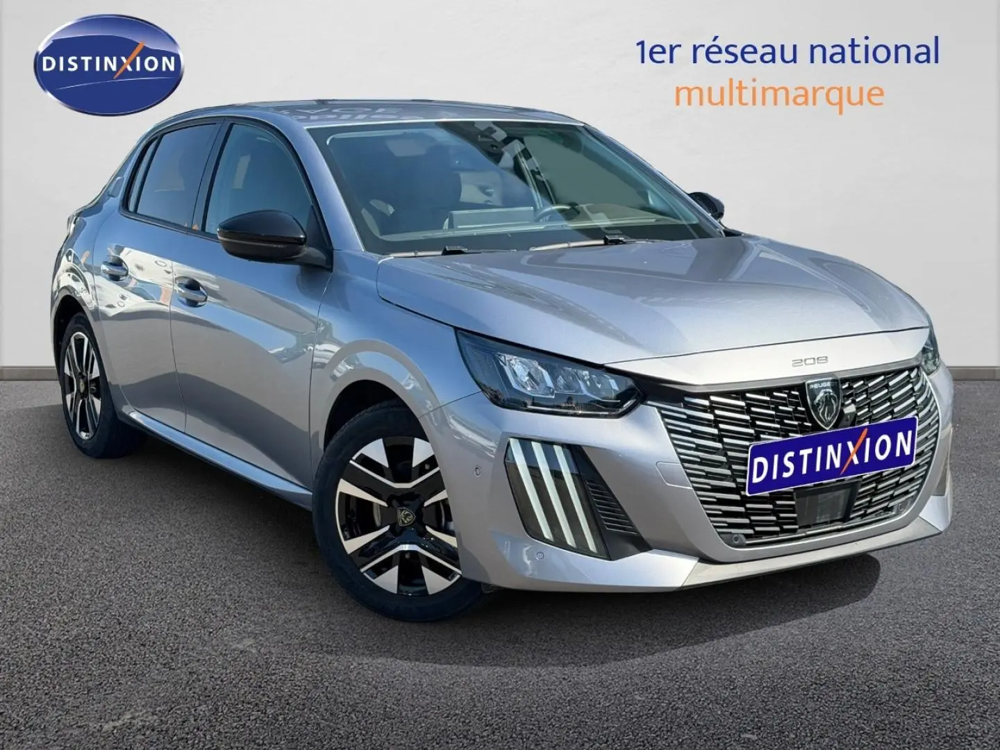 Peugeot 208 gris Artense vue 3/4 avant droit, avec calandre distinctive et jantes alliage noires et argentées.