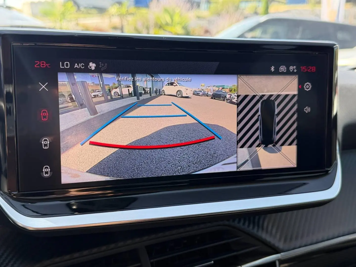 Écran tactile intérieur montrant la caméra de recul et vue 360° du Peugeot 208 gris Artense, tableau de bord moderne.