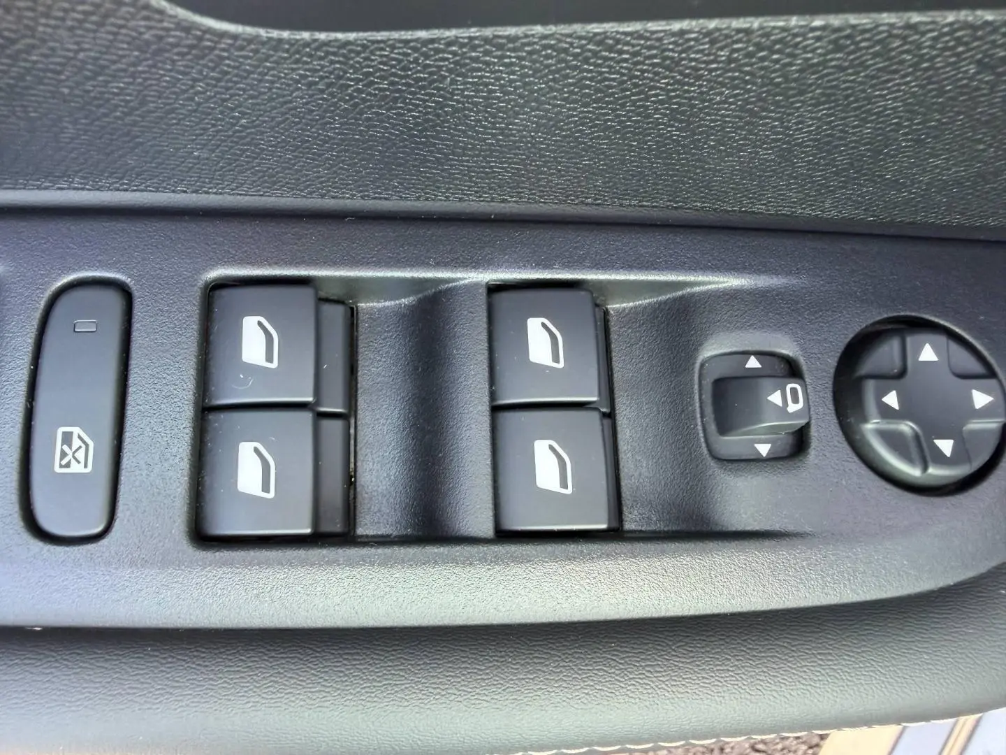 Gros plan sur les commandes des vitres et rétroviseurs côté gauche d'une Peugeot 208 gris Artense 2025.