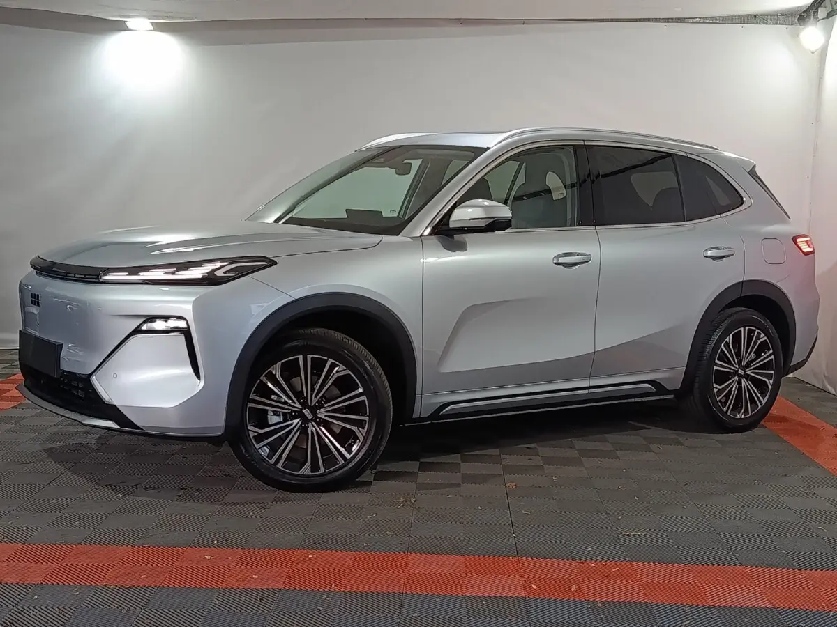 Vue de profil côté gauche d’un SUV Geely STARRAY gris clair avec jantes alliage et feux arrière allumés.