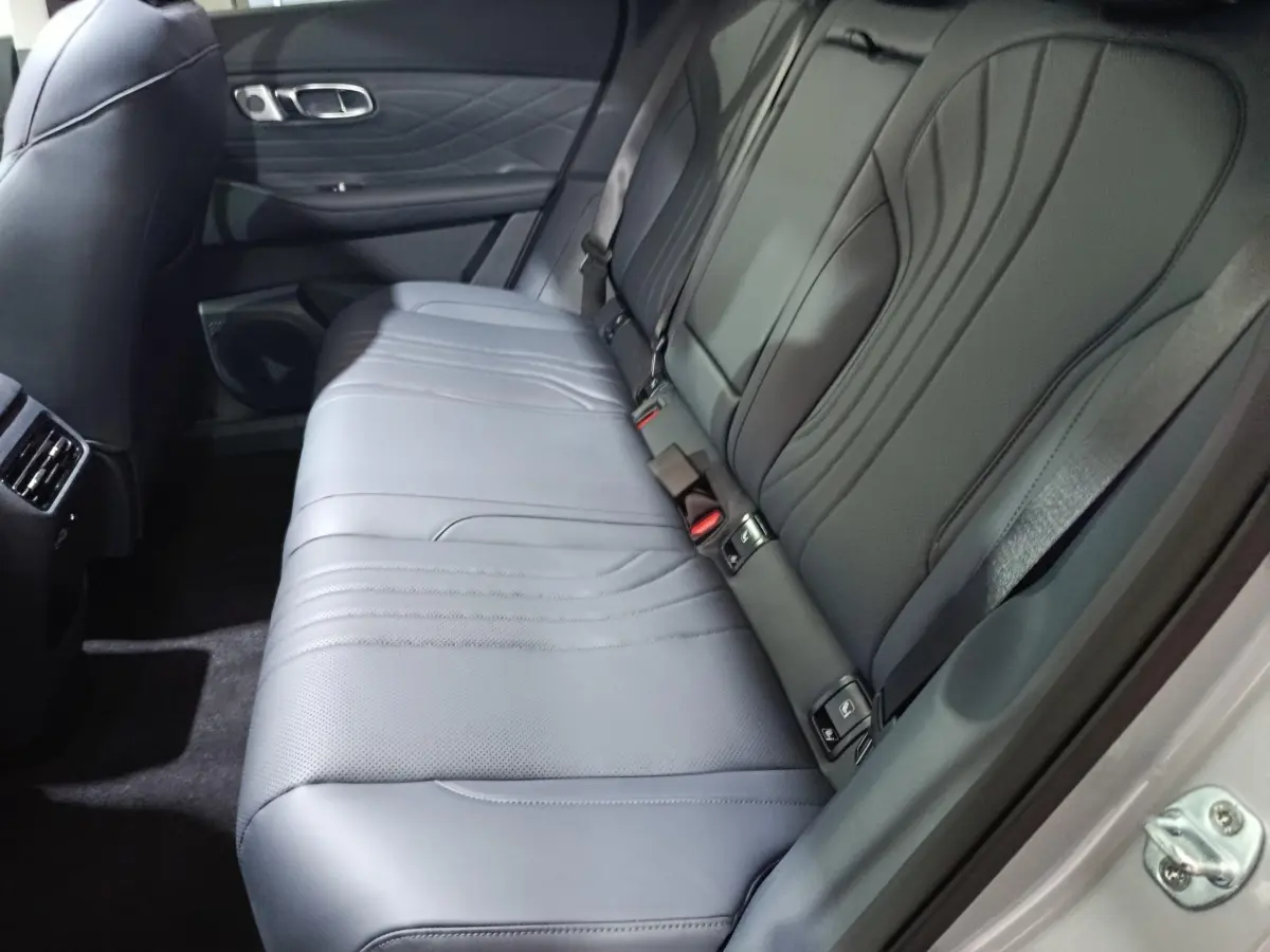 Vue intérieure côté droit des sièges arrière gris clair du Geely STARRAY 1.5 EM-I PHEV Max+ avec ceinture de sécurité visible.