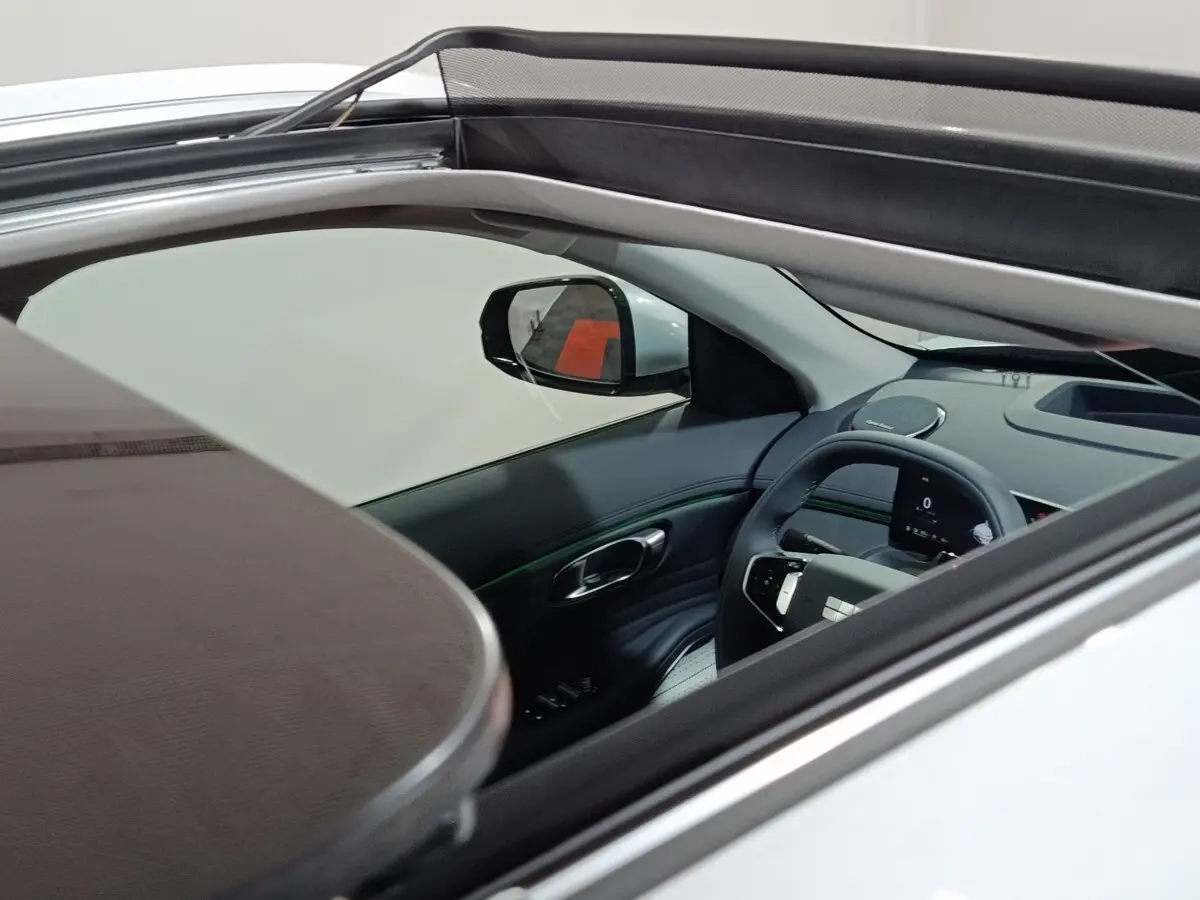 Vue intérieure côté conducteur d’un Geely Starray gris clair 2026 avec toit ouvrant et tableau de bord numérique.