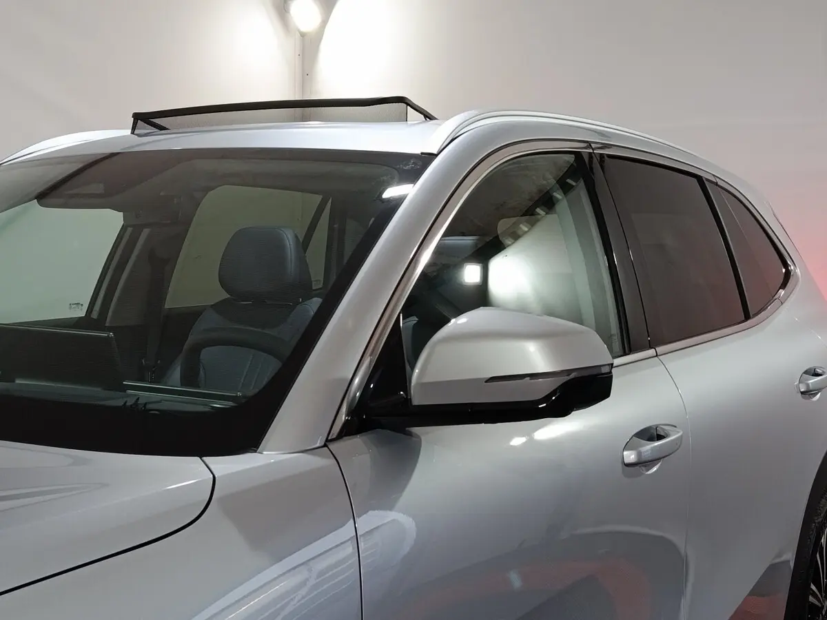 Vue de profil avant droit sur le Geely STARRAY gris clair avec toit ouvrant et rétroviseur intégré noir.
