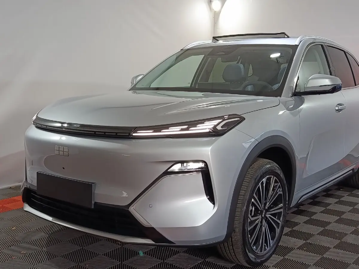 Vue 3/4 avant droit d'un SUV Geely STARRAY gris clair avec phares LED fins et toit vitré visible.